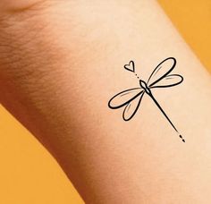 a small black dragonfly tattoo on the arm