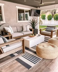 an outdoor living area with couches, chairs and rugs on the wooden floor