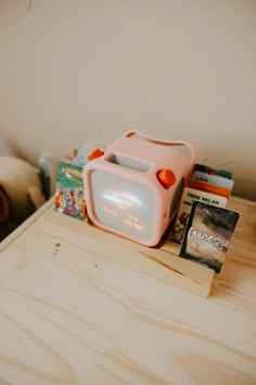 a pink radio sitting on top of a wooden table next to books and a teddy bear