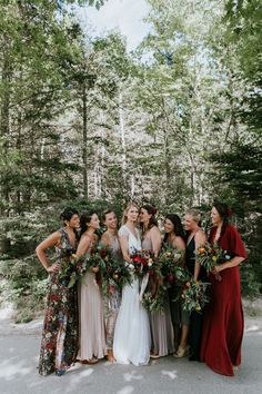 a group of women standing next to each other in front of some trees and bushes