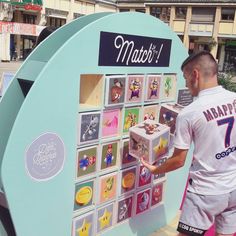 a man standing next to a display with many pictures on the front and back of it