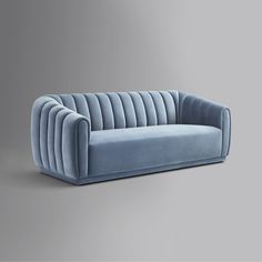 a blue velvet couch sitting on top of a gray floor