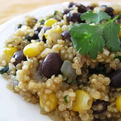 a white plate topped with black beans and corn next to a green garnish