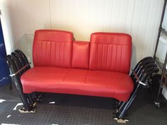 two red seats sitting next to each other in front of a white wall and black floor