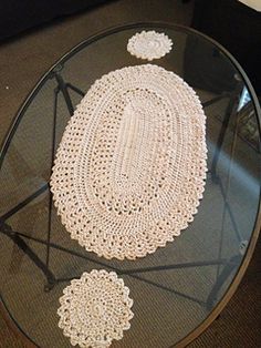 a glass table topped with a crocheted doily on top of a carpeted floor