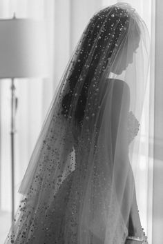 the back of a bride's wedding dress in black and white, with beaded veil