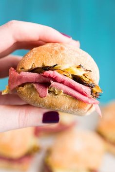 a hand holding a sandwich with meat and cheese