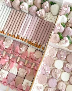 two trays filled with lots of pink and white cookies next to other desserts