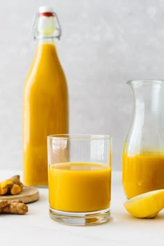 a glass filled with orange juice next to some sliced lemons and a bottle of orange juice