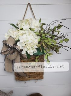 a basket with flowers hanging on the wall next to a sign that says farmhouse florals net