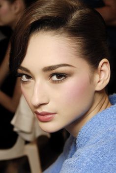 a close up of a person wearing a blue robe and eyeliner with long hair