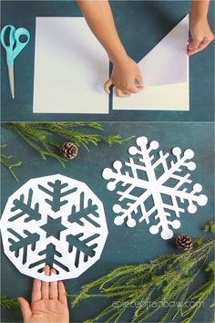 someone cutting out paper snowflakes with scissors and pine cones on the table next to them