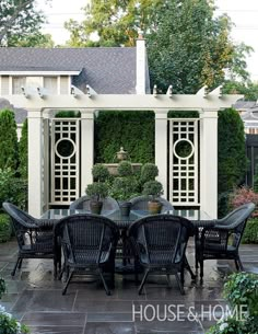 an outdoor dining area with chairs and table in front of a pergolated wall