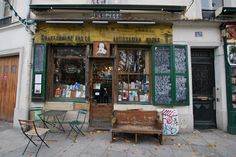 an old building with tables and chairs in front of it on the sidewalk outside,