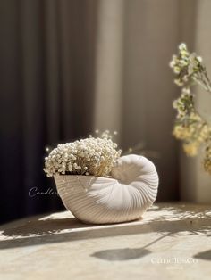 a vase filled with baby's breath flowers on top of a table next to a window