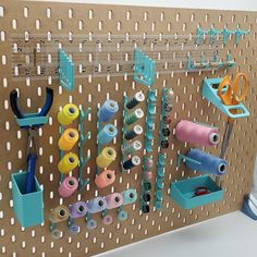 a peg board with scissors, spools and other crafting supplies on it