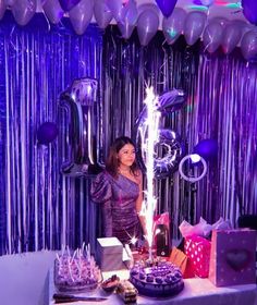 a woman standing in front of a table filled with cakes and balloons