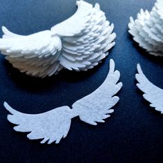 three white paper angel wings sitting on top of a table