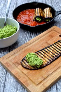 grilled fish with guacamole and salsa on a cutting board next to a skillet