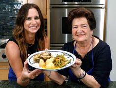 two women are smiling while holding a plate of food