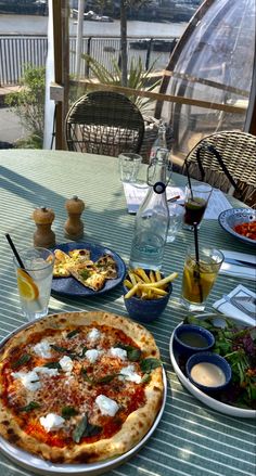 a pizza sitting on top of a table next to other plates and bowls filled with food