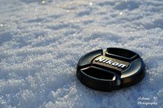 a black button sitting in the snow on top of it's headlight cover