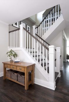 an entryway with white railing and wooden table in the foreground, hardwood flooring on the other side