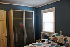 a bedroom with blue walls and a bed in front of a sliding glass closet door