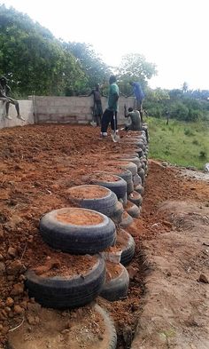 several people are standing around some tires in the dirt