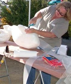 a woman is making something out of paper towels on a table outside with other items