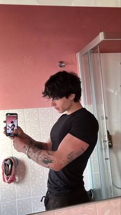 a man taking a selfie in front of a bathroom mirror with his cell phone