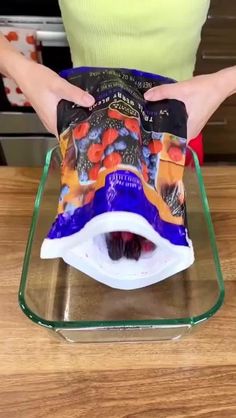 a woman is holding up some food in a bowl on top of a glass tray