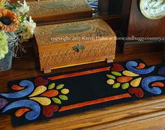 a wooden chest sitting on top of a table next to a clock and vase with flowers