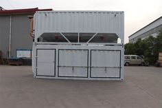 a large white container sitting in the middle of a parking lot next to a building