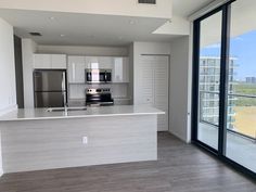 an empty kitchen with stainless steel appliances and sliding glass doors leading to the balcony area