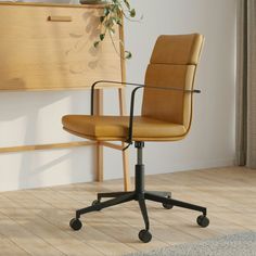 a brown office chair sitting on top of a hard wood floor next to a plant