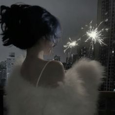 a woman in white dress standing on top of a building with fireworks coming out of her back