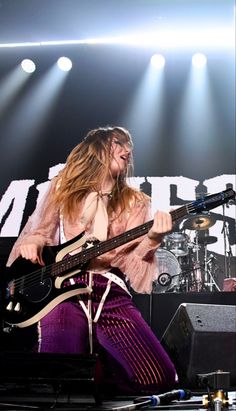 a woman with long hair playing guitar on stage