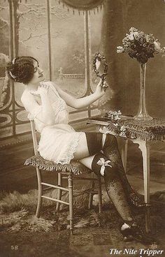 an old fashion photo of a woman sitting at a table with flowers in her hand