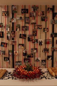 a table topped with fruit and pastries next to a wall covered in pictures