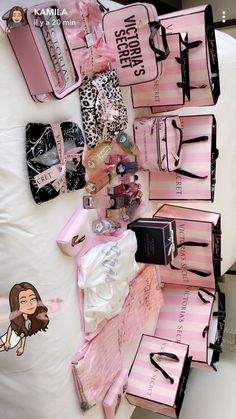 pink and black bags are stacked on top of each other in front of a white bed