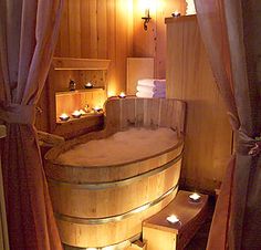 a wooden tub with candles lit in the corner and curtains open to let light inside