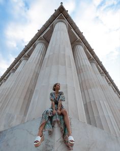 a woman sitting on the side of a tall building with her feet up in the air