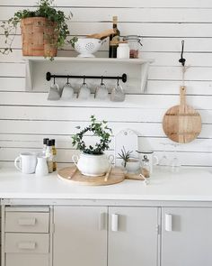 a kitchen counter with pots and pans on the wall above it is white painted wood paneling