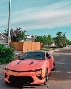 a red sports car parked on the side of the road in front of a house