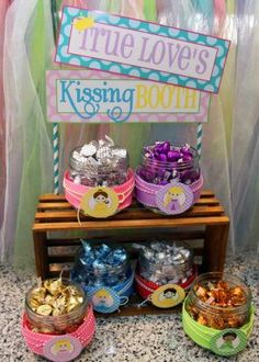 a table topped with lots of desserts next to a sign that says true love's kissing booth