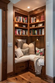 a wooden book shelf filled with lots of books next to a white couch and pillows