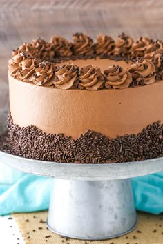 a chocolate cake with frosting and sprinkles sitting on a metal platter