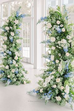 two tall white and blue flowers are in the middle of a room with large windows