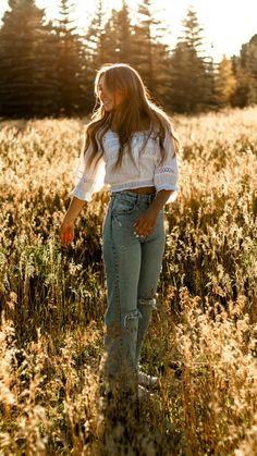 a woman standing in the middle of a field with her hands behind her back as if she were looking at something